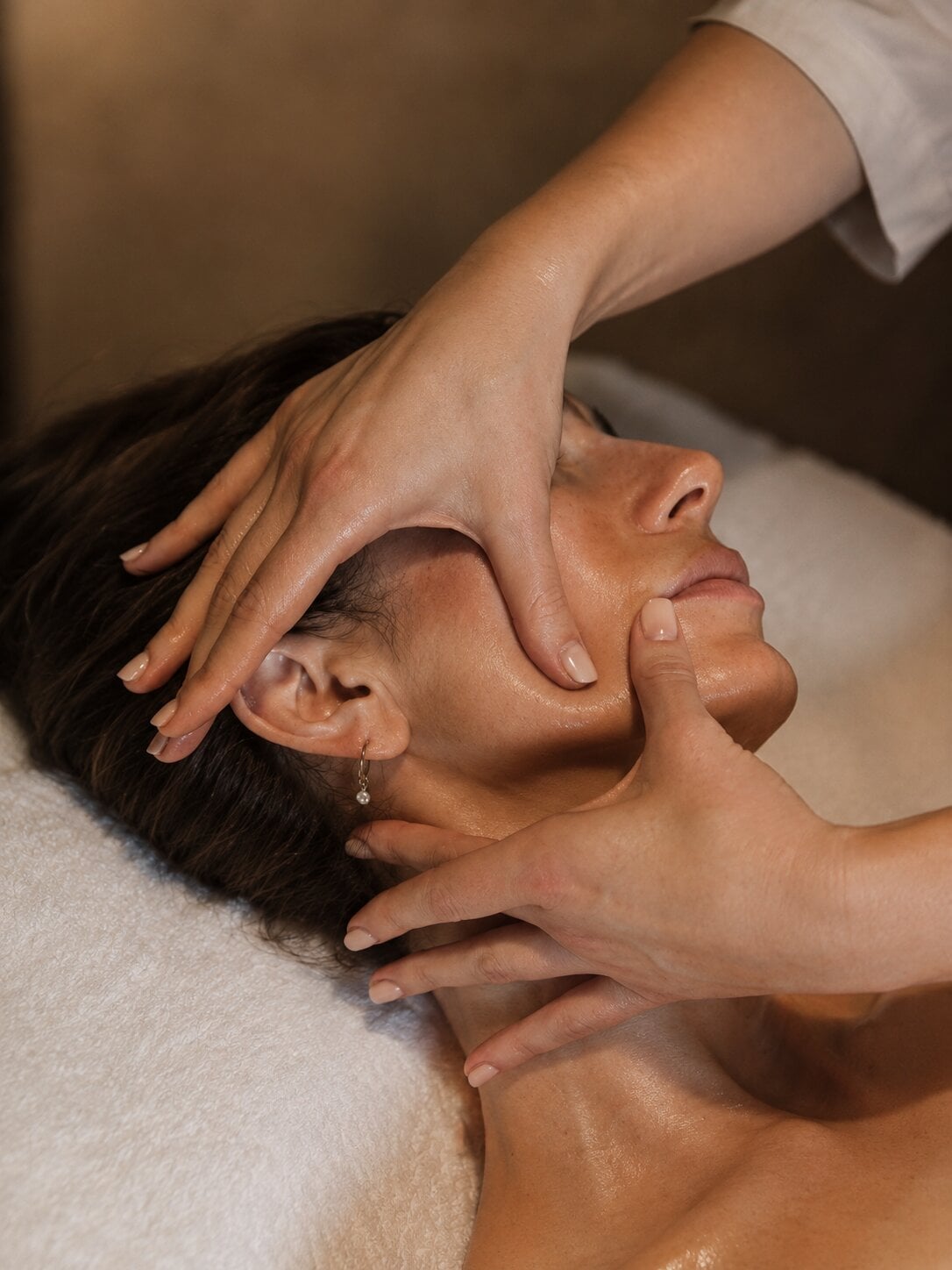 Mains d'une esthéticienne effectuant un massage du visage et du cou pendant un soin en studio